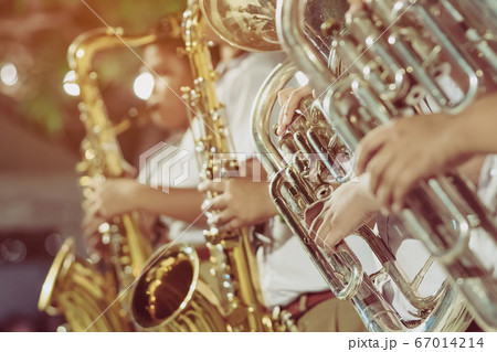 Male student with friends blow the euphonium with the band for performance on stage at night. 67014214