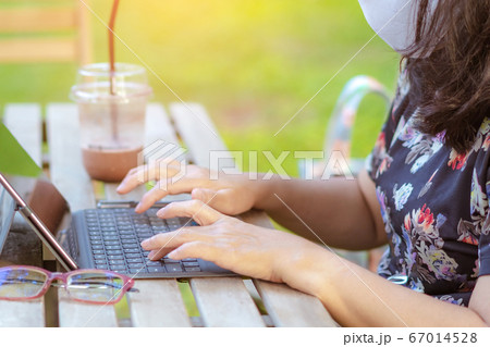 A quarantine woman wear a protective mask to prevent the spread of of the Corona virus (Covid-19) ,Use a laptop to work from home with green lawn and garden. New normal concept.Selective focus A quarantine woman wear a protective mask to prevent the spread of of the Corona virus (Covid-19) ,Use a laptop to work from home with green lawn and garden. New normal concept.Selective focus 67014528