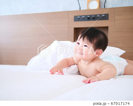 赤ちゃんがおむつ姿でベッドの上ではいはいしている 67017174