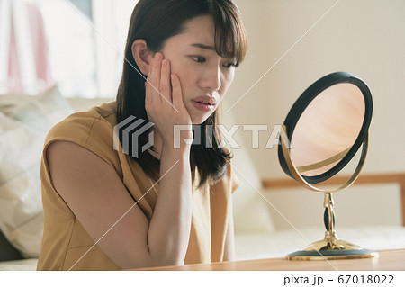 鏡を見て肌荒れを気にする30代の日本人女性イメージ 67018022