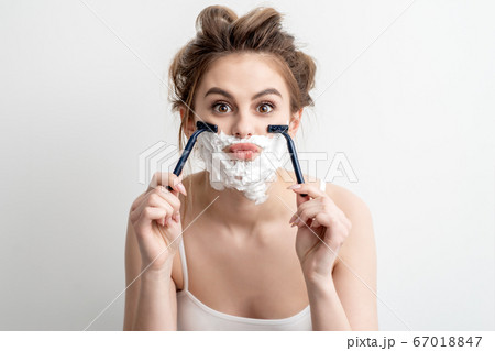 Woman with shaving foam on her face 67018847
