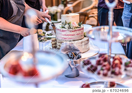 cutting a beautiful delicious Wedding cake in many tiers with fresh wild flowers and roses 67024696