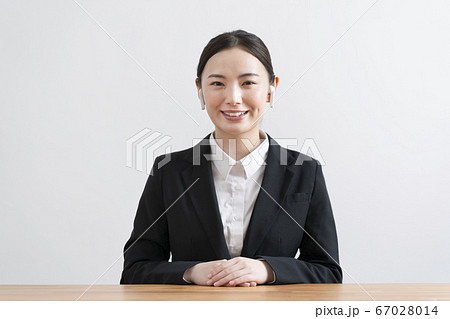 ワイヤレスヘッドホンをつけてカメラ目線で話す笑顔のスーツ姿の若い女性 ワイヤレスヘッドホンをつけてカメラ目線で話す笑顔のスーツ姿の若い女性 67028014
