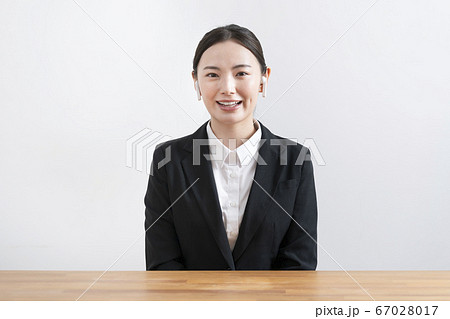 ワイヤレスヘッドホンをつけてカメラ目線で話すスーツ姿の若い女性 ワイヤレスヘッドホンをつけてカメラ目線で話すスーツ姿の若い女性 67028017