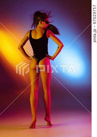 Beautiful seductive girl in fashionable swimsuit on disco bicolored neon studio background in neon light. Summer, resort, fashion and weekend concept Beautiful seductive girl in fashionable swimsuit on disco bicolored neon studio background in neon light. Summer, resort, fashion and weekend concept 67029757