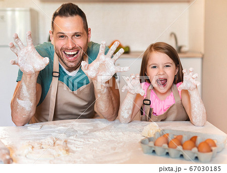 Father And Little Daughter Showing Dirty Hands Making Dough Indoors Father And Little Daughter Showing Dirty Hands Making Dough Indoors 67030185