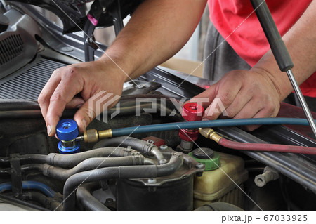Mechanic fixing air condition at modern car 67033925