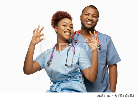 Couple of beautiful african-american doctors or nurses smiling isolated over white studio background Couple of beautiful african-american doctors or nurses smiling isolated over white studio background 67033982