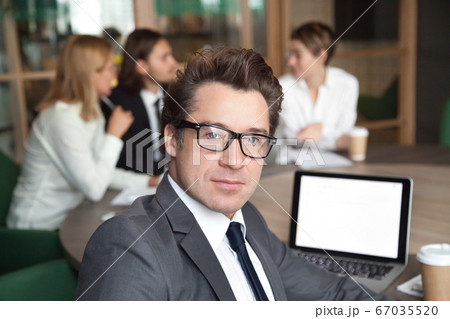 Middle-aged businessman investor wearing glasses looking at came Middle-aged businessman investor wearing glasses looking at came 67035520