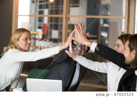 Happy business team giving high-five together promising engageme Happy business team giving high-five together promising engageme 67035523