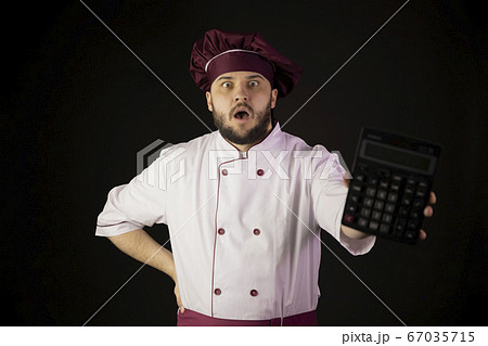 Shocked chef man in uniform holds calculator in panic looks at camera incur loss 67035715