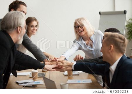 Happy smiling corporate team join hands together at group meetin 67036233