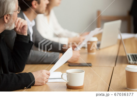 Attentive senior businessman focused on listening at group meeti Attentive senior businessman focused on listening at group meeti 67036377