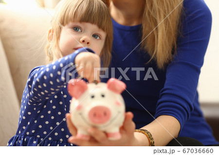 Child little girl arm putting coins into piggybank 67036660