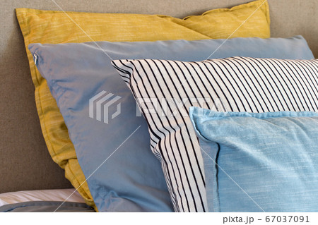 Closeup of Yellow and light blue pillows in a row on the bed, modern retro decoration for home, pastel light colors colorful bright 67037091