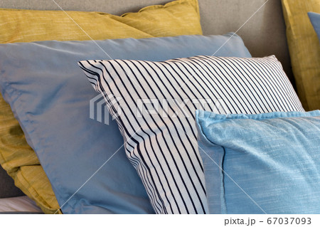 Closeup of Yellow and light blue pillows in a row on the bed, modern retro decoration for home, pastel light colors colorful bright 67037093