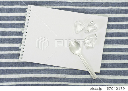 ランチョンマットの上に置いたスケッチブックと氷とスプーン 67040179