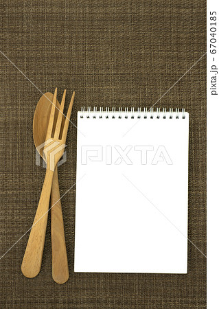ランチョンマットの上に置いたスケッチブックとフォークとスプーン 67040185