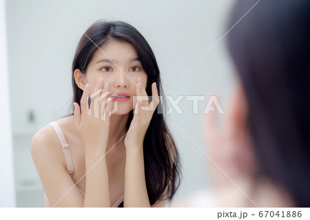 Beautiful young asian woman smiling look at mirror of checking face with skin care and cosmetic. Beautiful young asian woman smiling look at mirror of checking face with skin care and cosmetic. 67041886