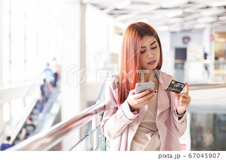 asian young woman red hair holding smartphone and credit card. 67045907