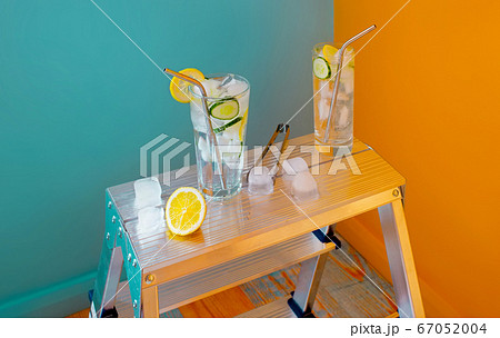 Refreshing tonic and gin Tom Collins cocktail or lemonade with lemon ice and cucumber on contrast colorful blue and yellow background. Refreshing tonic and gin Tom Collins cocktail or lemonade with lemon ice and cucumber on contrast colorful blue and yellow background. 67052004