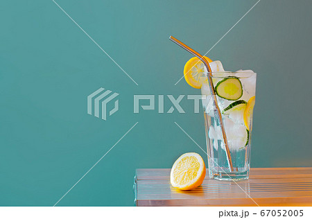 Refreshing tonic and gin Tom Collins cocktail or lemonade with lemon ice and cucumber on contrast colorful blue and yellow background.  67052005