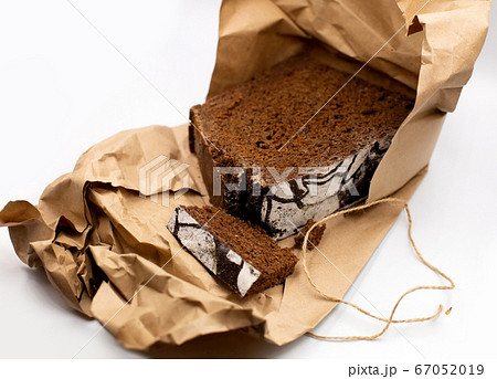 Home cooked healthy wholegrain rye dark traditional Russian bread loaf in rustic craft paper on white battleground. Home cooked healthy wholegrain rye dark traditional Russian bread loaf in rustic craft paper on white battleground. 67052019