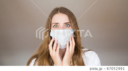 Portrait of a girl who covered her face with a mask. Frightened eyes of the patient. Portrait of a girl who covered her face with a mask. Frightened eyes of the patient. 67052991