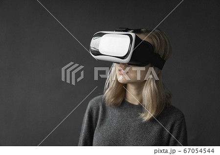 Young woman wearing virtual reality goggles headset, vr box. Connection, technology, new generation, progress concept. Girl trying to touch objects in virtual reality. 67054544