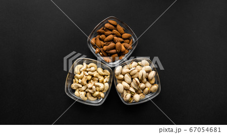 Almond, pistachio and cashew in a small plates which standing on a black table. Nuts is a healthy vegetarian protein and nutritious food. Almond, pistachio and cashew in a small plates which standing on a black table. Nuts is a healthy vegetarian protein and nutritious food. 67054681