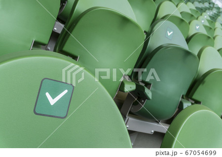 Empty plastic seats in a stadium. Stickers intended to promote social distancing in the arena. Empty plastic seats in a stadium. Stickers intended to promote social distancing in the arena. 67054699