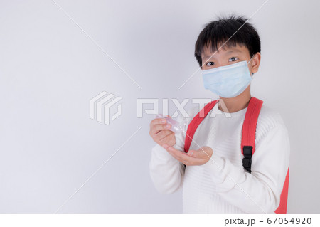 School boy wearing face mask and applying hand sanitizer, Back to school after covid-19 pandemic. School boy wearing face mask and applying hand sanitizer, Back to school after covid-19 pandemic. 67054920