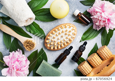 Concept SPA and Wellness. Massage brush, cosmetic oils and soap. Light background with peony flowers. 67056924