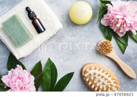 Concept SPA and Wellness. Massage brush, cosmetic oils and soap. Light background with peony flowers. Copy space 67056925