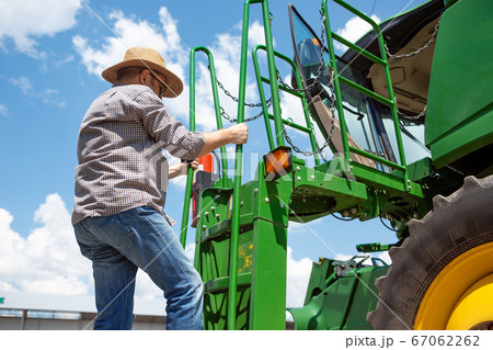 A farmer with a tractor, combine at a field in sunlight. Confident, bright colors A farmer with a tractor, combine at a field in sunlight. Confident, bright colors 67062262