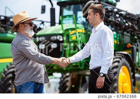 A farmer with a tractor, combine at a field in sunlight. Confident, bright colors A farmer with a tractor, combine at a field in sunlight. Confident, bright colors 67062366
