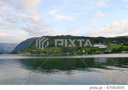 ノルウェー　ハダンゲルフィヨルド、ウルヴィク地区ホテルより南西側の水面とのどかな建物を望む 67063605