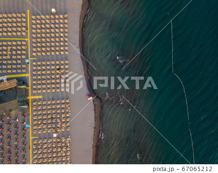 Aerial view of sandy beach with yellow sunbeds and wooden umbrellas at sunset 67065212