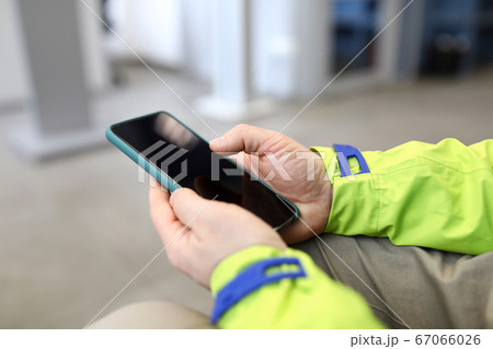 Close-up male hands in jacket hold smartphone 67066026