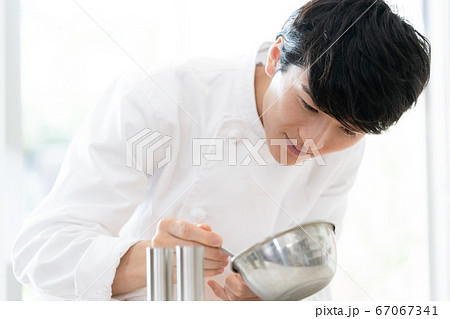 ソースをかける男性調理師の写真素材
