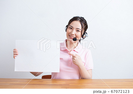ヘッドセットを付けてコピーボードを持つ女性の写真素材