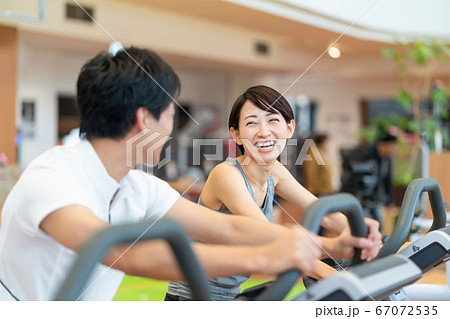 スポーツジムでエアロバイクをするカップル スポーツジムでエアロバイクをするカップル 67072535