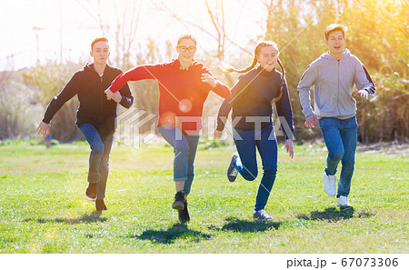 Cheerful teens running on green lawn Cheerful teens running on green lawn 67073306