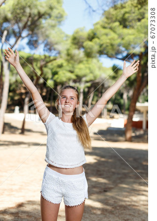 Portrait of teenage cute girl standing in green park at sunny day 67073308