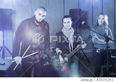 Three bandmates posing together with musical instruments in rehe 67074243