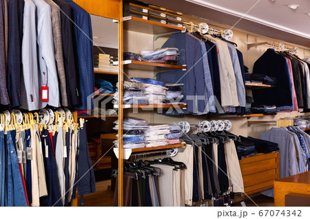 Fashion modern men clothes displayed on shelves and hanger racks in clothing store 67074342