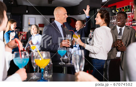 Cheerful male and female colleagues having fun on corporate party in bar Cheerful male and female colleagues having fun on corporate party in bar 67074502