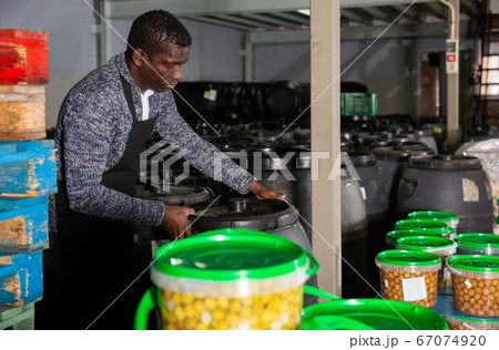 Worker stacking plastic barrels of pickled olives Worker stacking plastic barrels of pickled olives 67074920