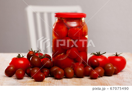 Glass jar with pickled tomatoes and fresh tomatoes 67075490