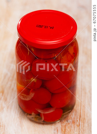 Glass jar of canned red tomatoes on wooden table 67075555
